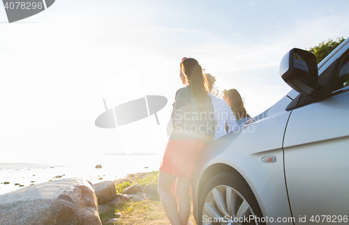 Image of happy teenage girls or women near car at seaside