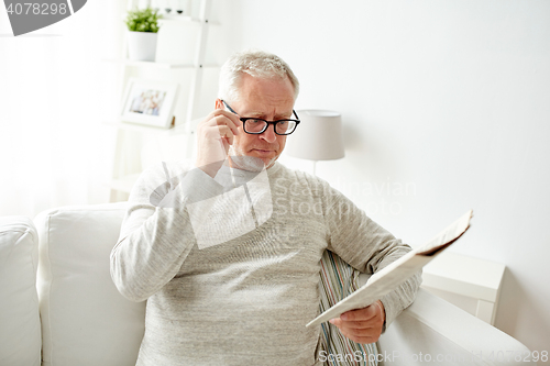 Image of senior man in glasses reading newspaper at home