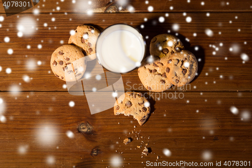 Image of close up of oat cookies and milk on wooden table