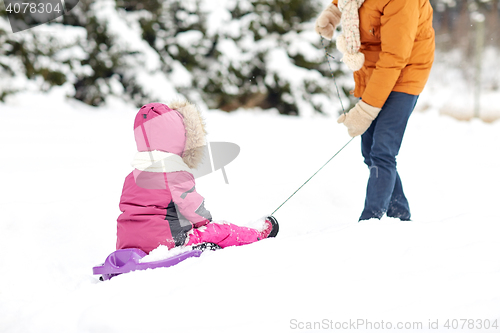 Image of father pulling sled with child in winter