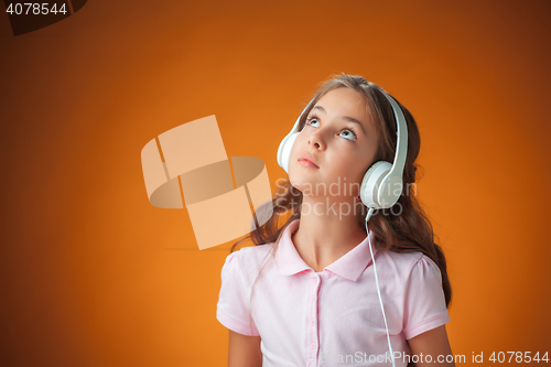 Image of The cute cheerful little girl on orange background