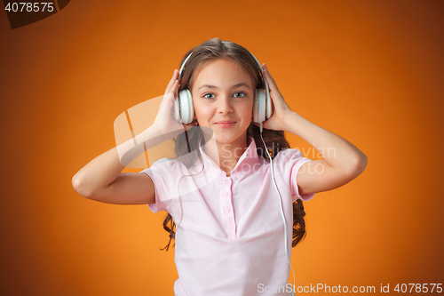 Image of The cute cheerful little girl on orange background