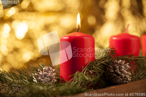 Image of First candle burning on a red Advent wreath