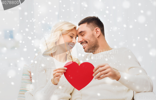 Image of happy couple with red heart hugging at home