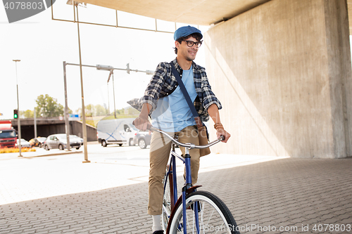 Image of young hipster man with bag riding fixed gear bike