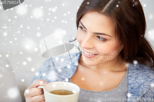 Image of happy woman with cup of tea at home