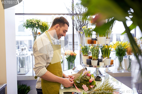 Image of smiling florist man making bunch at flower shop