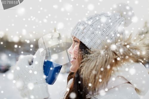 Image of happy young woman with tea cup outdoors in winter