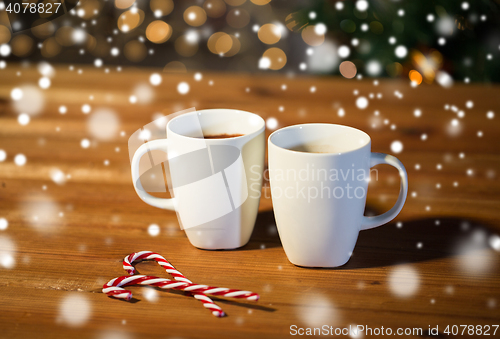Image of christmas candy canes and cups on wooden table