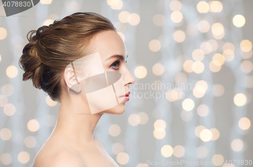 Image of beautiful young woman face over holidays lights