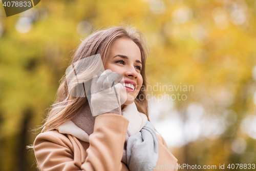 Image of woman calling on smartphone in autumn park