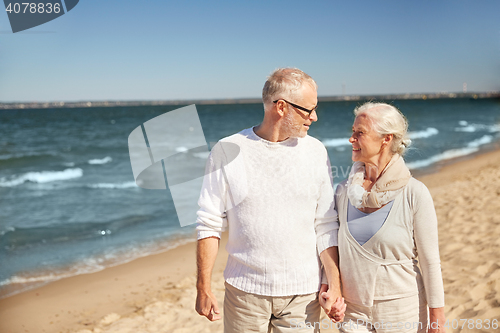 Image of happy senior couple walking along summer beach