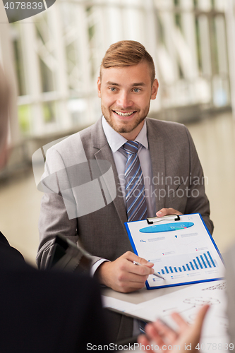 Image of smiling businessman with graph at business meeting