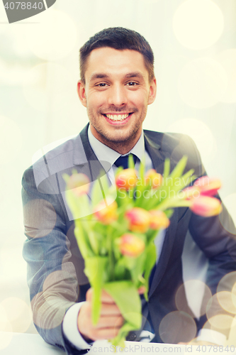 Image of smiling handsome man giving bouquet of flowers