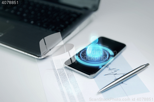 Image of close up of smartphone, laptop and pen on table