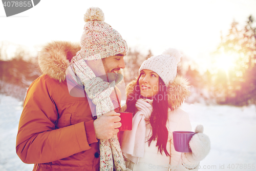 Image of happy couple with tea cups over winter landscape