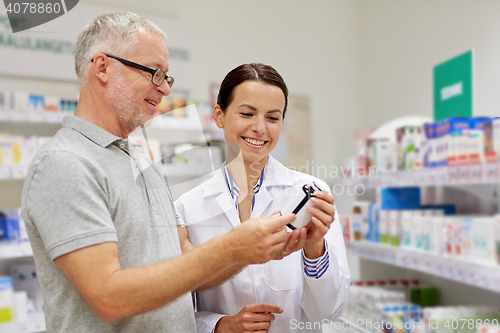 Image of pharmacist showing drug to senior man at pharmacy