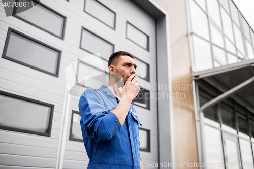 Image of auto mechanic smoking cigarette at car workshop