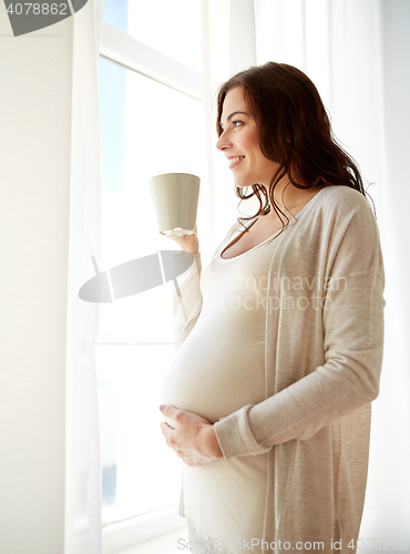 Image of happy pregnant woman with cup drinking tea at home