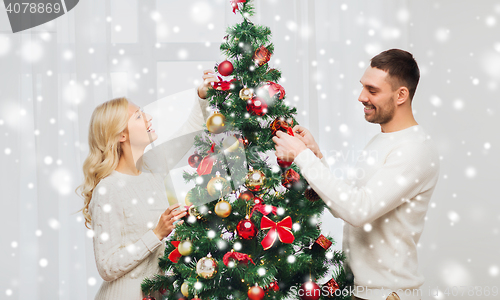 Image of happy couple decorating christmas tree at home