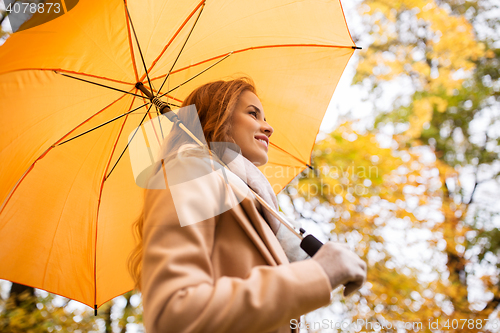 Image of happy woman with umbrella walking in autumn park