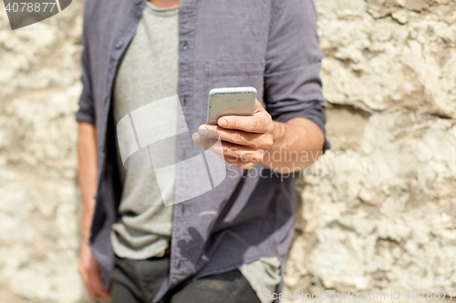 Image of close up of man with smartphone at stone wall
