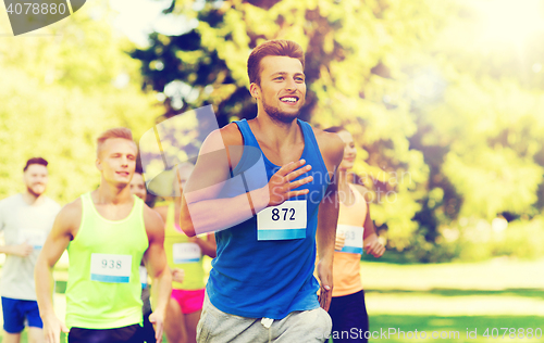 Image of happy young sportsmen racing wit badge numbers