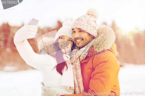 Image of happy couple taking selfie by smartphone in winter