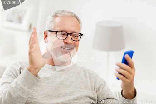 Image of senior man having video call on smartphone at home
