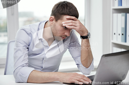 Image of stressed businessman with laptop at office