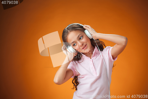 Image of The cute cheerful little girl on orange background