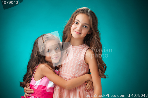 Image of The two cheerful little girls on orange background