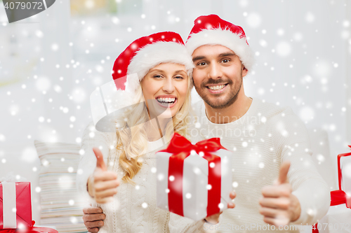 Image of happy couple with christmas gifts and thumbs up