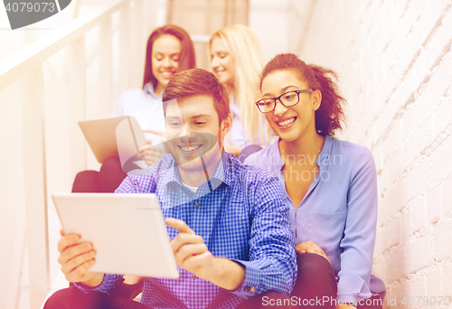 Image of team with tablet pc computer sitting on staircase