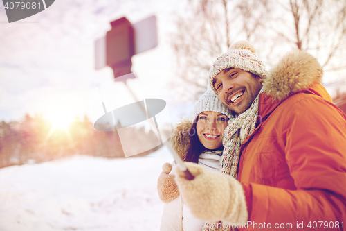 Image of happy couple taking selfie by smartphone in winter