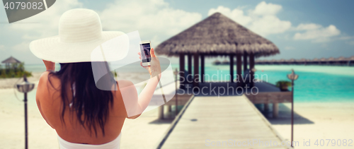 Image of smiling young woman taking selfie with smartphone