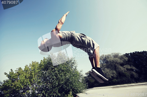 Image of sporty young man jumping in summer park