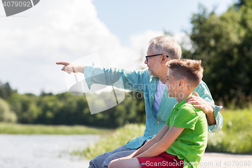 Image of grandfather and grandson sitting on river berth