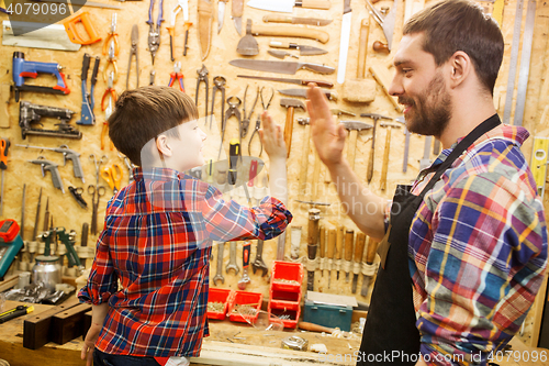 Image of father and little son making high five at workshop