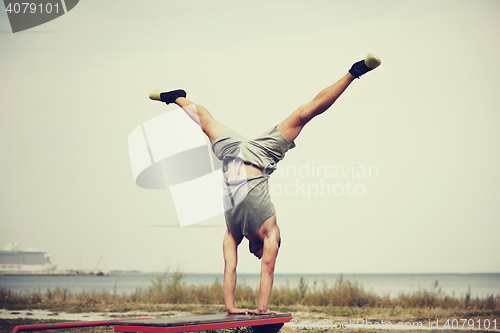 Image of young man exercising on bench outdoors