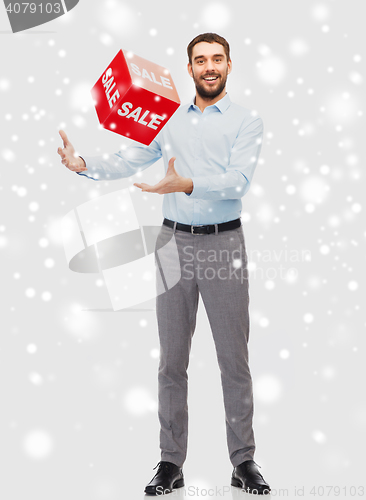 Image of smiling man playing with red sale sign over snow