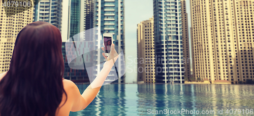 Image of woman taking selfie with smartphone over city pool