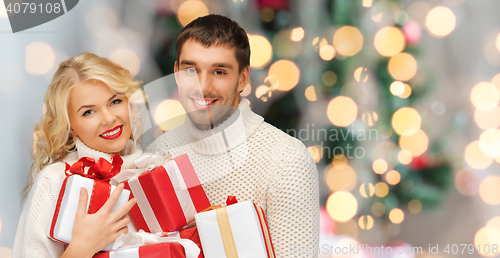 Image of happy couple in sweaters holding christmas gifts