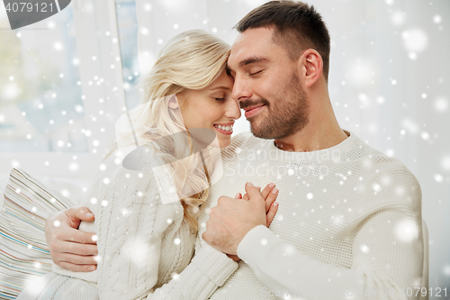 Image of happy couple covered with plaid on sofa at home