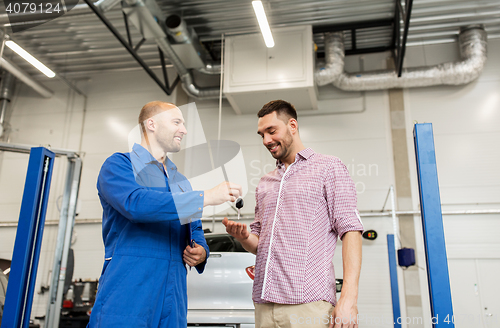 Image of auto mechanic giving key to man at car shop