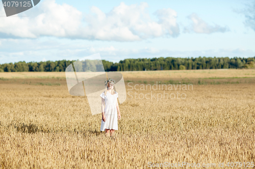 Image of happy young woman in flower wreath on cereal field