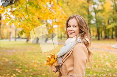 Image of beautiful woman with maple leaves in autumn park