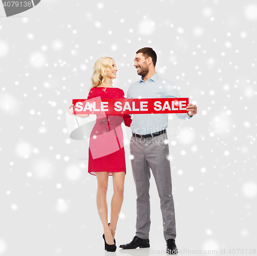 Image of happy couple with red sale sign over snow