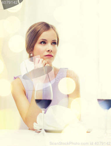 Image of upset woman with glass of whine waiting for date