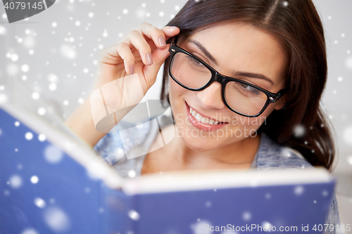 Image of happy woman in glasses reading book at home